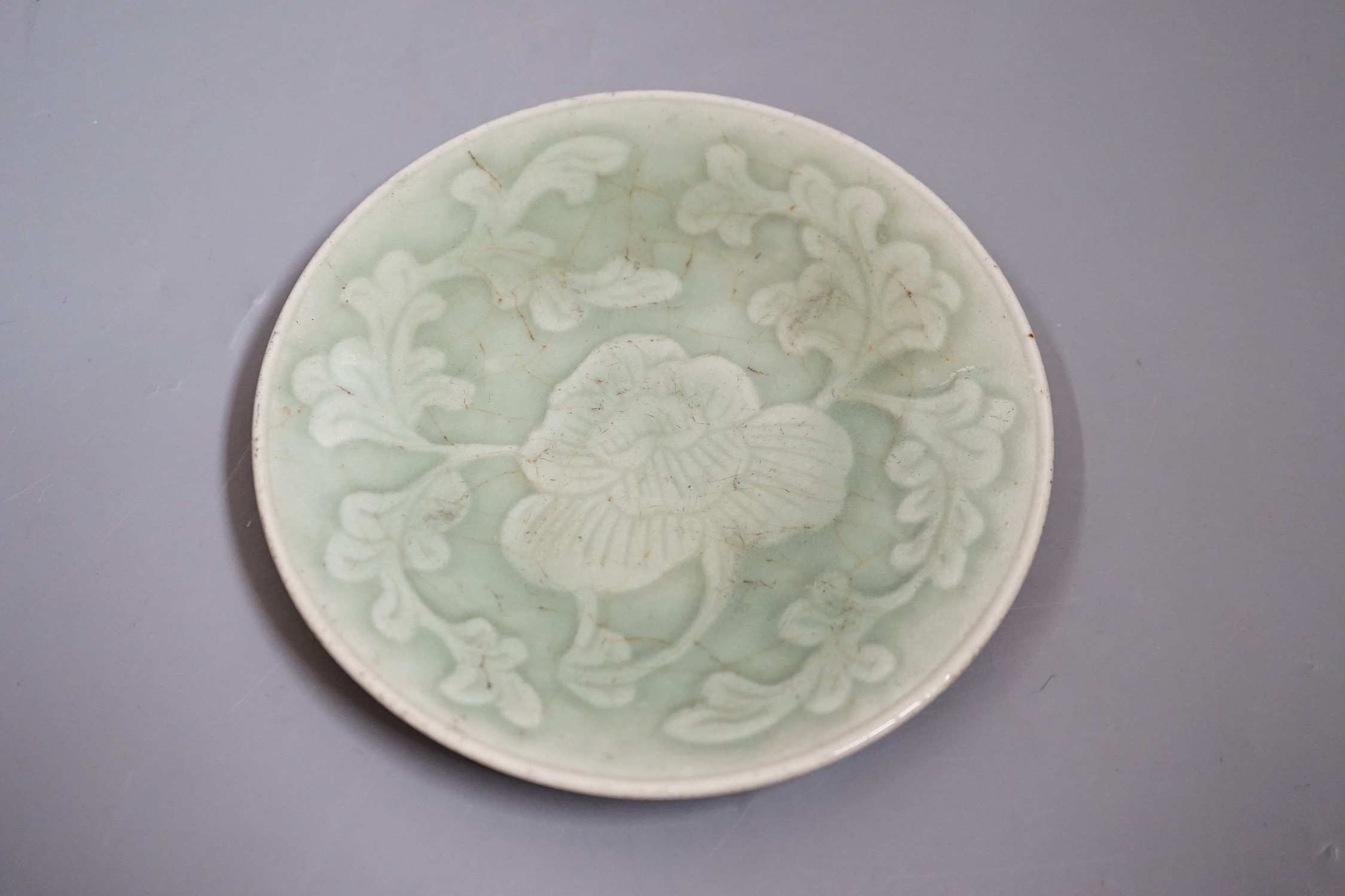 A Chinese carved celadon dish, Qing dynasty, 15cm diameter